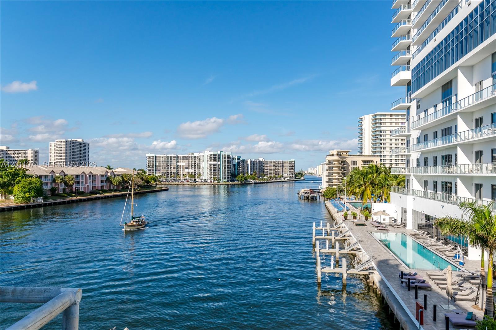 A high-angle view of a waterway with a sailboat, surrounding apartment buildings, and a pool — 4010 S Ocean Dr # R1808, Hollywood FL 33019, HOLLYWOOD, FL