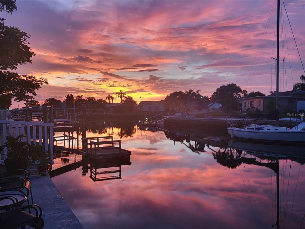 A vibrant sunset reflects over a calm canal with docks and moored sailboats — 4865 SHELL STREAM BOULEVARD, NEW PORT RICHEY, FL