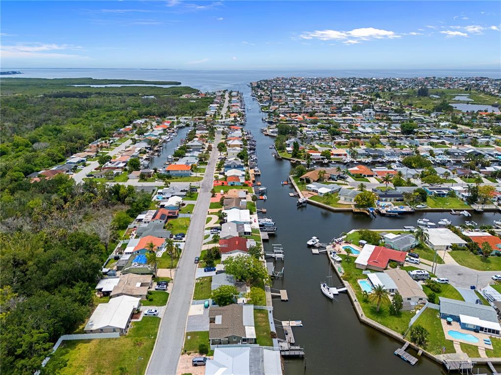 An aerial view shows a residential neighborhood with houses lining a canal and a street — 4865 SHELL STREAM BOULEVARD, NEW PORT RICHEY, FL