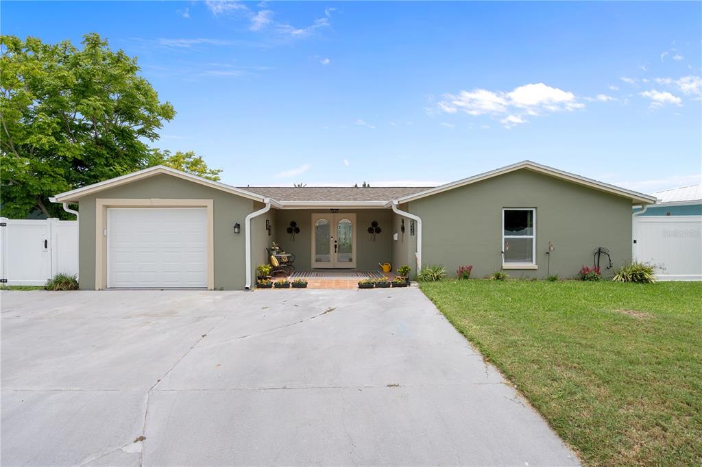 A single-story house with a green exterior, a white garage door, and a concrete driveway — 4865 SHELL STREAM BOULEVARD, NEW PORT RICHEY, FL