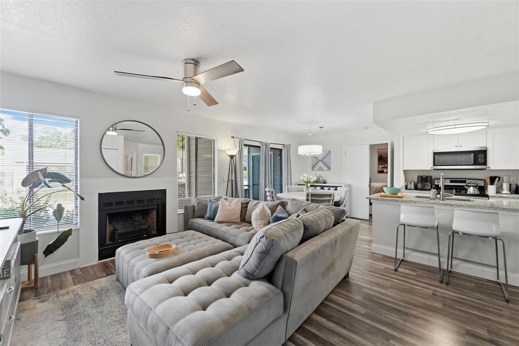 A living room with a grey sectional sofa, fireplace, and open kitchen with bar seating — 537 SUN RIDGE PLACE UNIT 107, ALTAMONTE SPRINGS, FL