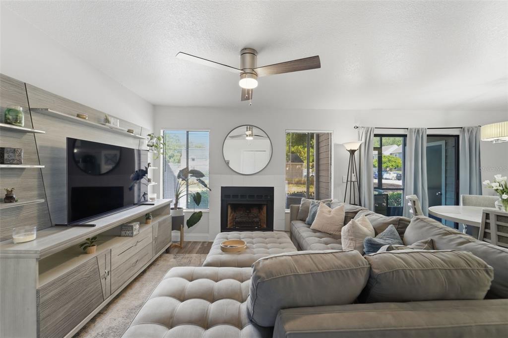 A living room features a gray sectional sofa, a fireplace, and a wall-mounted television unit — 537 SUN RIDGE PLACE UNIT 107, ALTAMONTE SPRINGS, FL