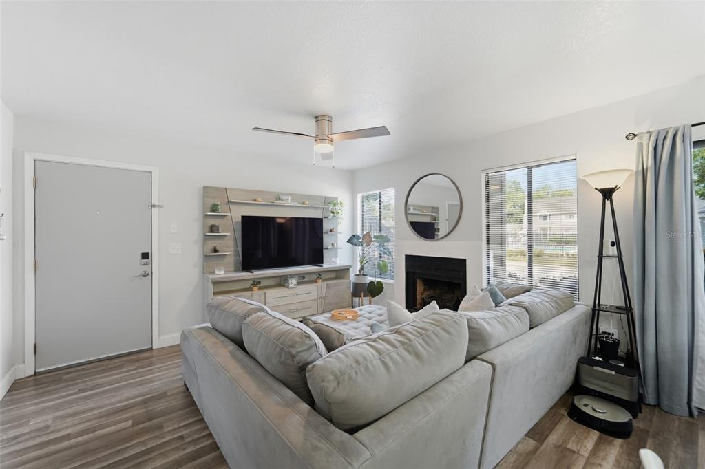 A living room features a sectional sofa, a fireplace, and a wall-mounted television unit — 537 SUN RIDGE PLACE UNIT 107, ALTAMONTE SPRINGS, FL