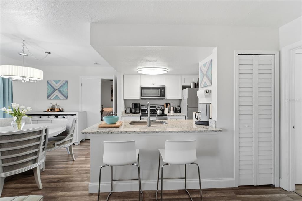 A kitchen with white cabinets, granite countertops, and a breakfast bar with two stools — 537 SUN RIDGE PLACE UNIT 107, ALTAMONTE SPRINGS, FL