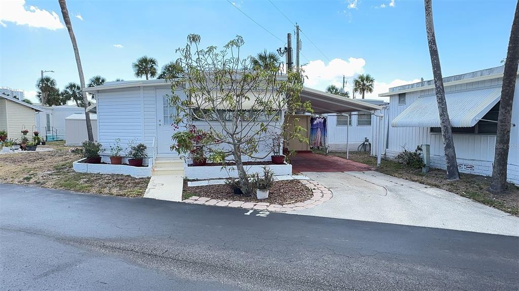 A white mobile home with a carport, a small front garden, and a paved driveway — 4851 W GANDY BOULEVARD UNIT B4L12, TAMPA, FL