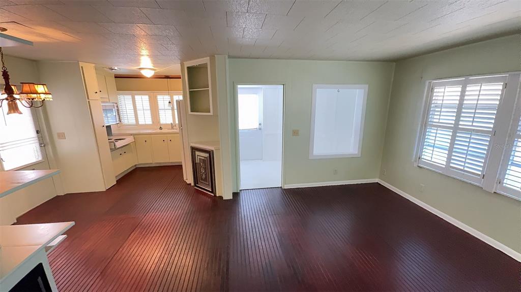 A living room with dark wood-look flooring leads into a kitchen and a hallway — 4851 W GANDY BOULEVARD UNIT B4L12, TAMPA, FL
