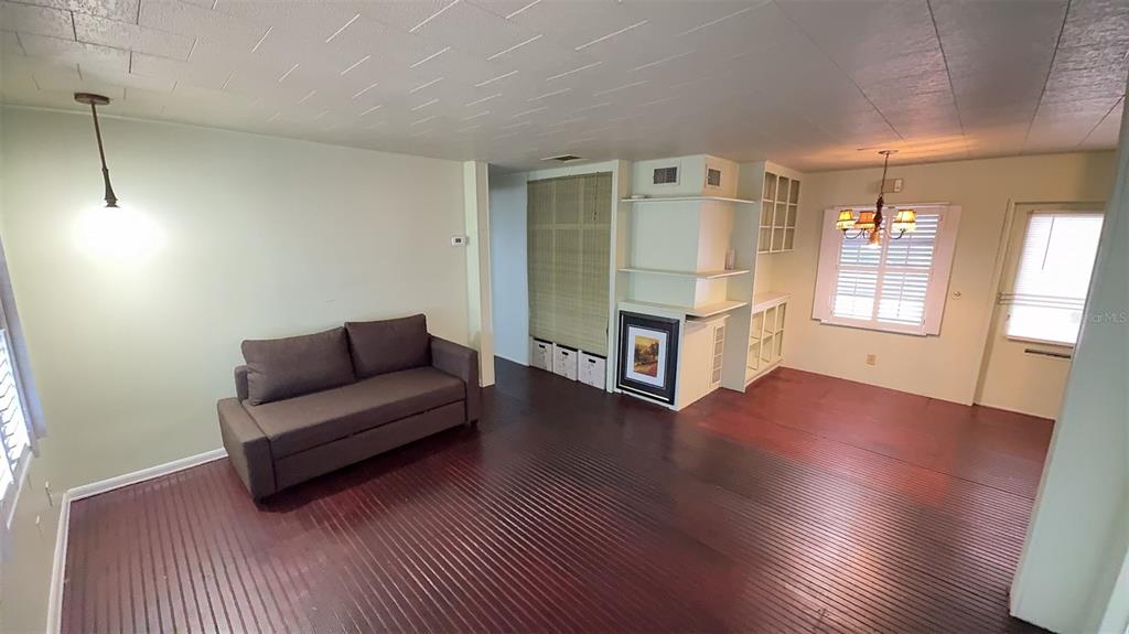 A living room with dark wood flooring, a brown sofa, and a built-in shelving unit — 4851 W GANDY BOULEVARD UNIT B4L12, TAMPA, FL