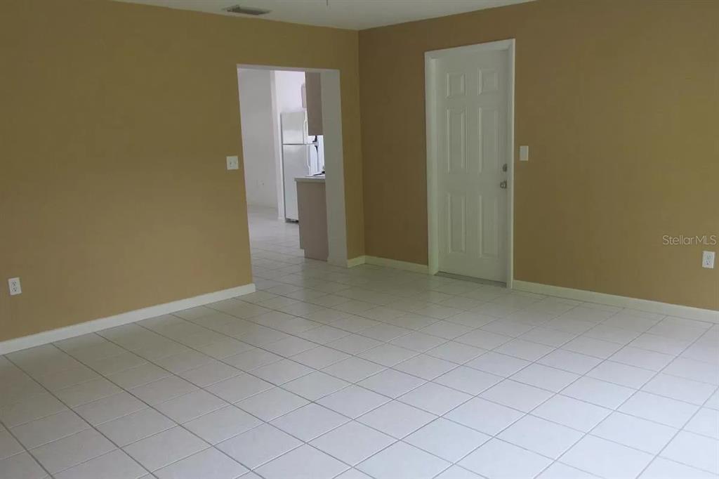 An interior view of a room with beige walls, white tile flooring, and a doorway — 2911 BENTLEY STREET, SARASOTA, FL