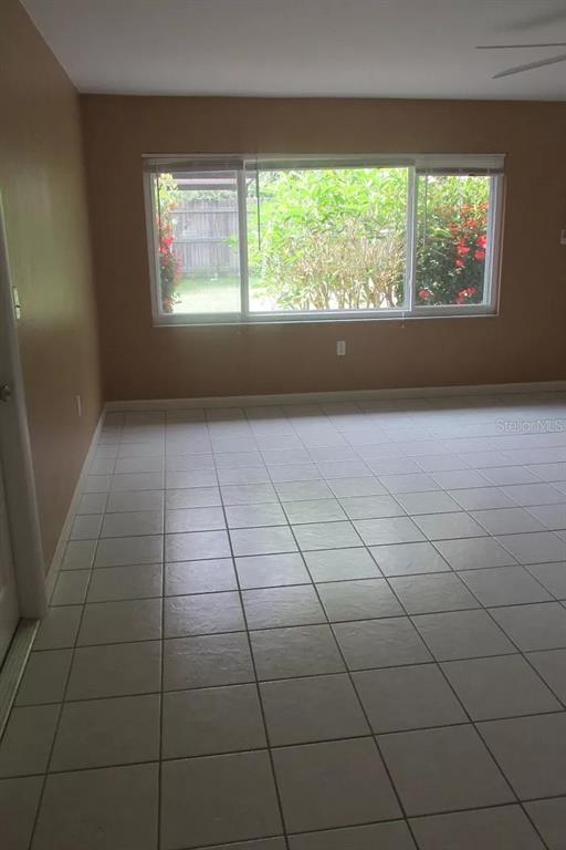 An empty room with light-colored tile flooring and a large window overlooking a backyard — 2911 BENTLEY STREET, SARASOTA, FL