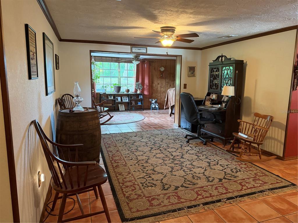 A living room with a large area rug, wooden rocking chairs, and a desk area — 12204 BEAR CREEK LANE, HUDSON, FL