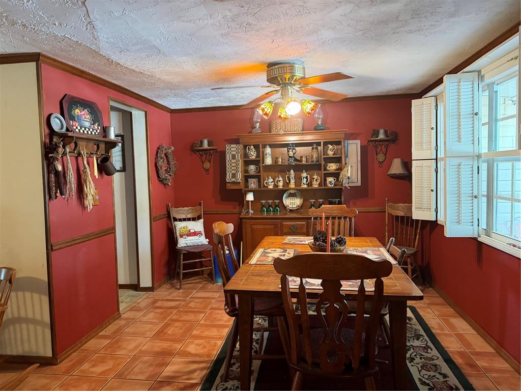 A dining room features red walls, a wooden hutch, a dining table, and tile flooring — 12204 BEAR CREEK LANE, HUDSON, FL