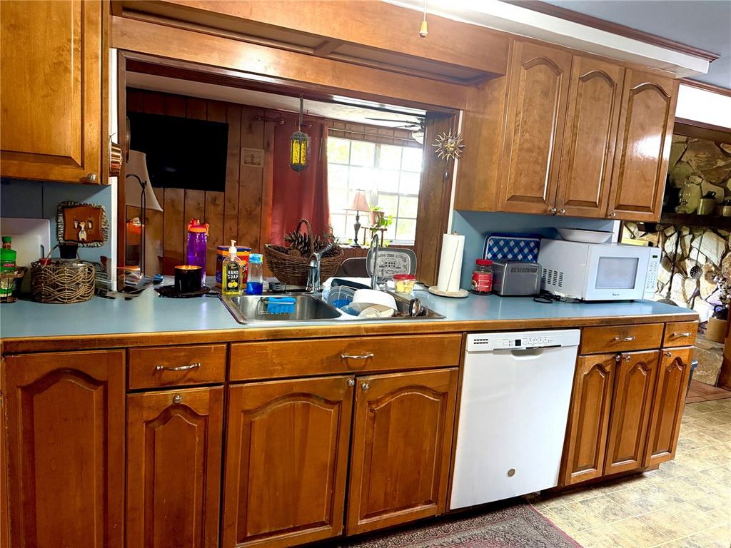 A kitchen features wood cabinets, a blue countertop, a stainless steel sink, and a dishwasher — 12204 BEAR CREEK LANE, HUDSON, FL