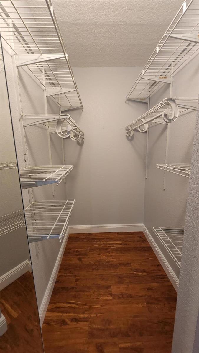 A walk-in closet with white wire shelving, light gray walls, and wood-look flooring — 527 Shady Pine Way # C1, FL 33415, FL