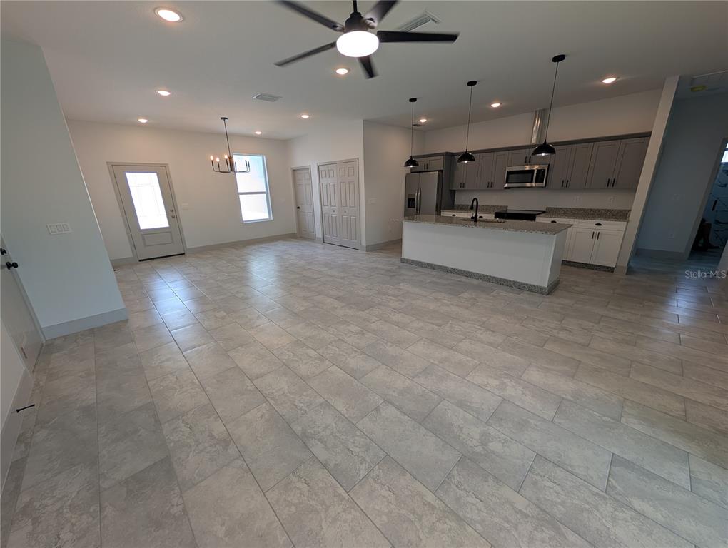 An open-concept kitchen and living area features gray cabinetry, granite countertops, and tile flooring — 1246 HERSCHELL STREET, LAKELAND, FL