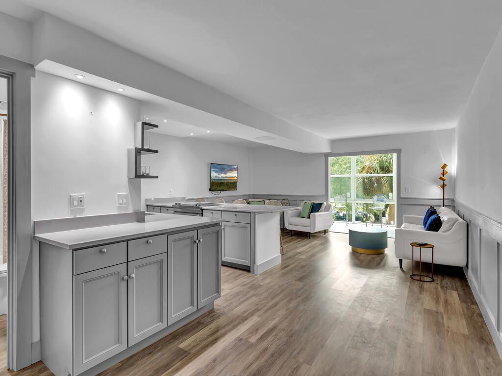 A modern kitchen and living area with gray cabinetry, wood flooring, and a white sofa — 275 Date Palm Road # 304, Vero Beach FL 32963, VERO BEACH, FL