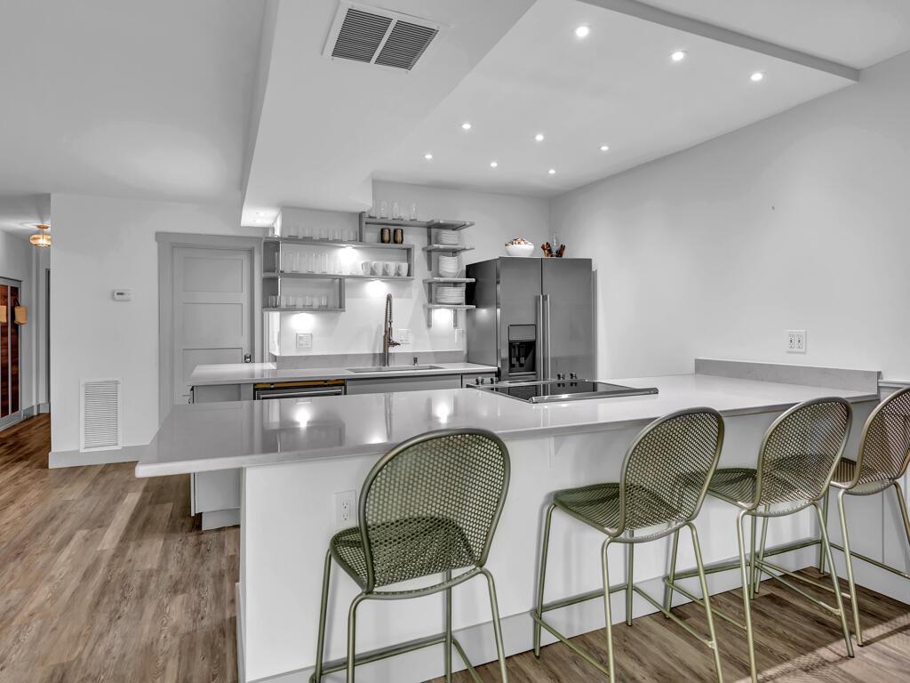 A modern kitchen features a white quartz island with bar seating and stainless steel appliances — 275 Date Palm Road # 304, Vero Beach FL 32963, VERO BEACH, FL