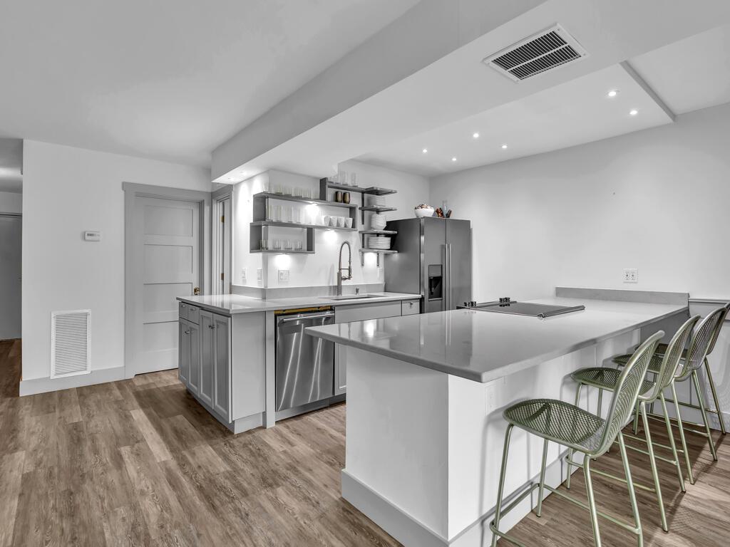 A modern kitchen features gray cabinetry, stainless steel appliances, a quartz island, and bar seating — 275 Date Palm Road # 304, Vero Beach FL 32963, VERO BEACH, FL