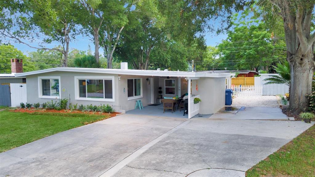 A single-story gray house with a concrete driveway, a covered porch, and a white fence — 1555 SHIRLEY PLACE, LARGO, FL