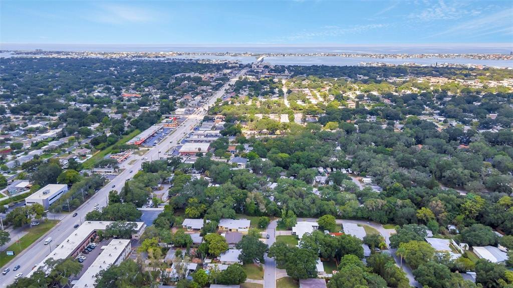 An aerial view shows a suburban neighborhood with a main road and dense tree cover — 1555 SHIRLEY PLACE, LARGO, FL