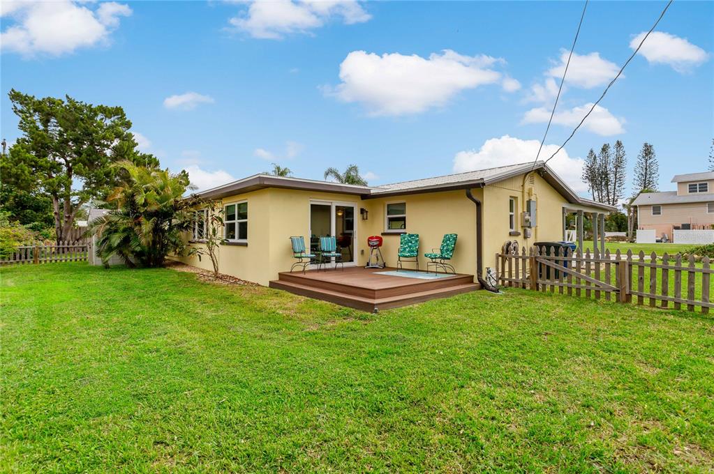 A yellow house with a wooden deck and a fenced backyard under a blue sky — 1675 BLAKEMORE LANE, SARASOTA, FL