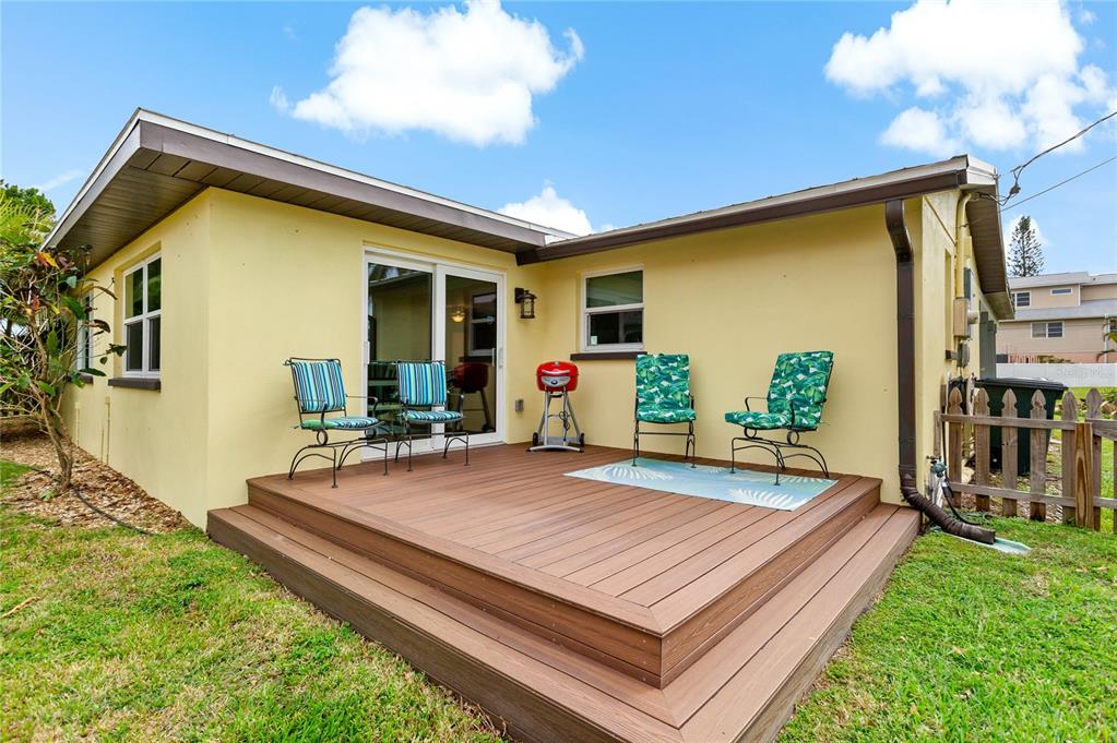 A yellow house exterior features a wooden deck with patio furniture and a small grill — 1675 BLAKEMORE LANE, SARASOTA, FL