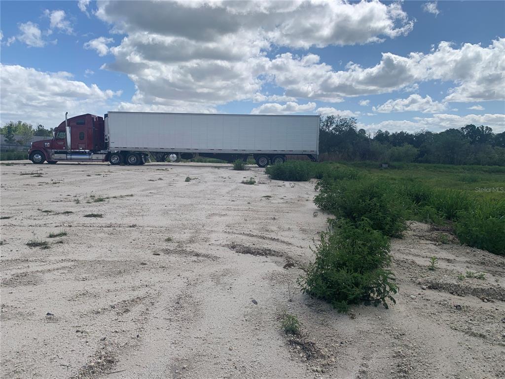 A red semi-truck is parked on a large, unpaved dirt lot under a cloudy sky — 0 RHINO ROAD, LAKELAND, FL