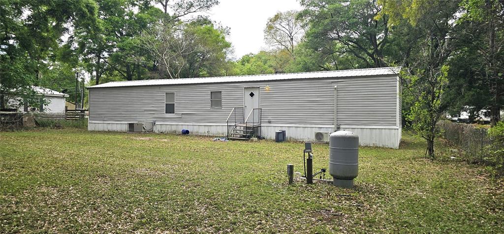A single-story manufactured home with gray siding sits on a grassy lot with trees — 6605 NW 60TH COURT, OCALA, FL