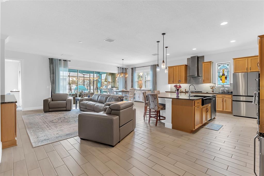 An open-concept kitchen and living area features wood cabinets, a large island, and tile flooring — 2764 GREENLANDS STREET, ST CLOUD, FL