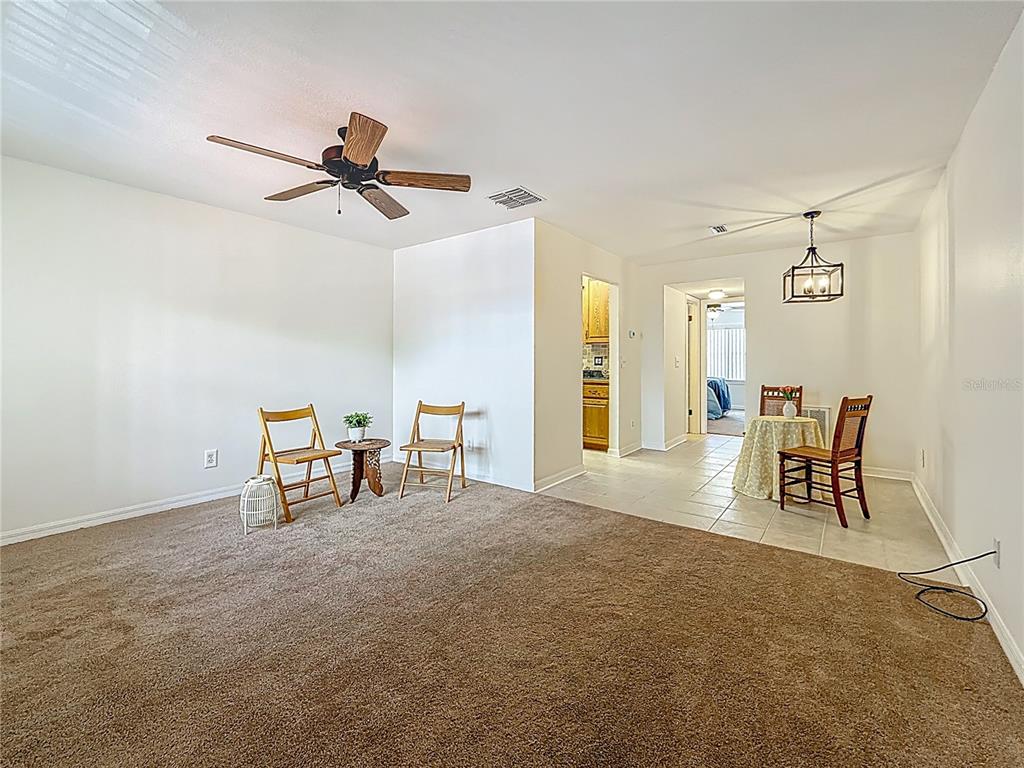 A living room with brown carpeting features a ceiling fan and an adjacent tiled dining area — 2442 ENTERPRISE ROAD UNIT 6, CLEARWATER, FL