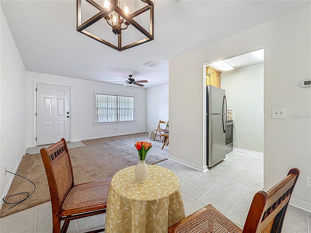 A dining area with a small table and chairs opens into a carpeted living room — 2442 ENTERPRISE ROAD UNIT 6, CLEARWATER, FL