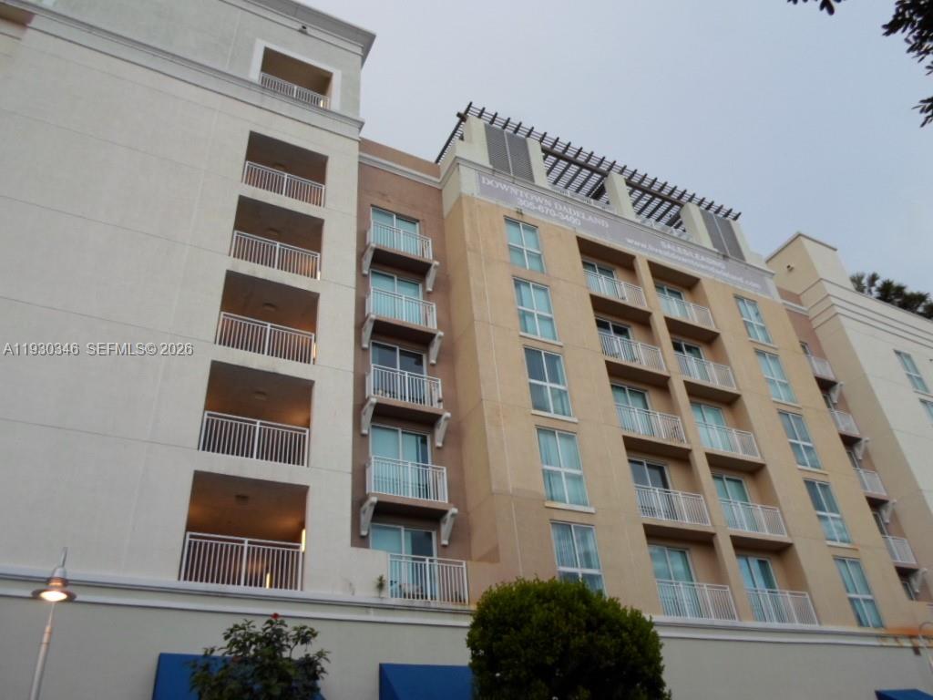 A low-angle exterior view of a multi-story apartment building with balconies and large windows — 7275 SW 90th Way # 611, Miami FL 33156, MIAMI, FL