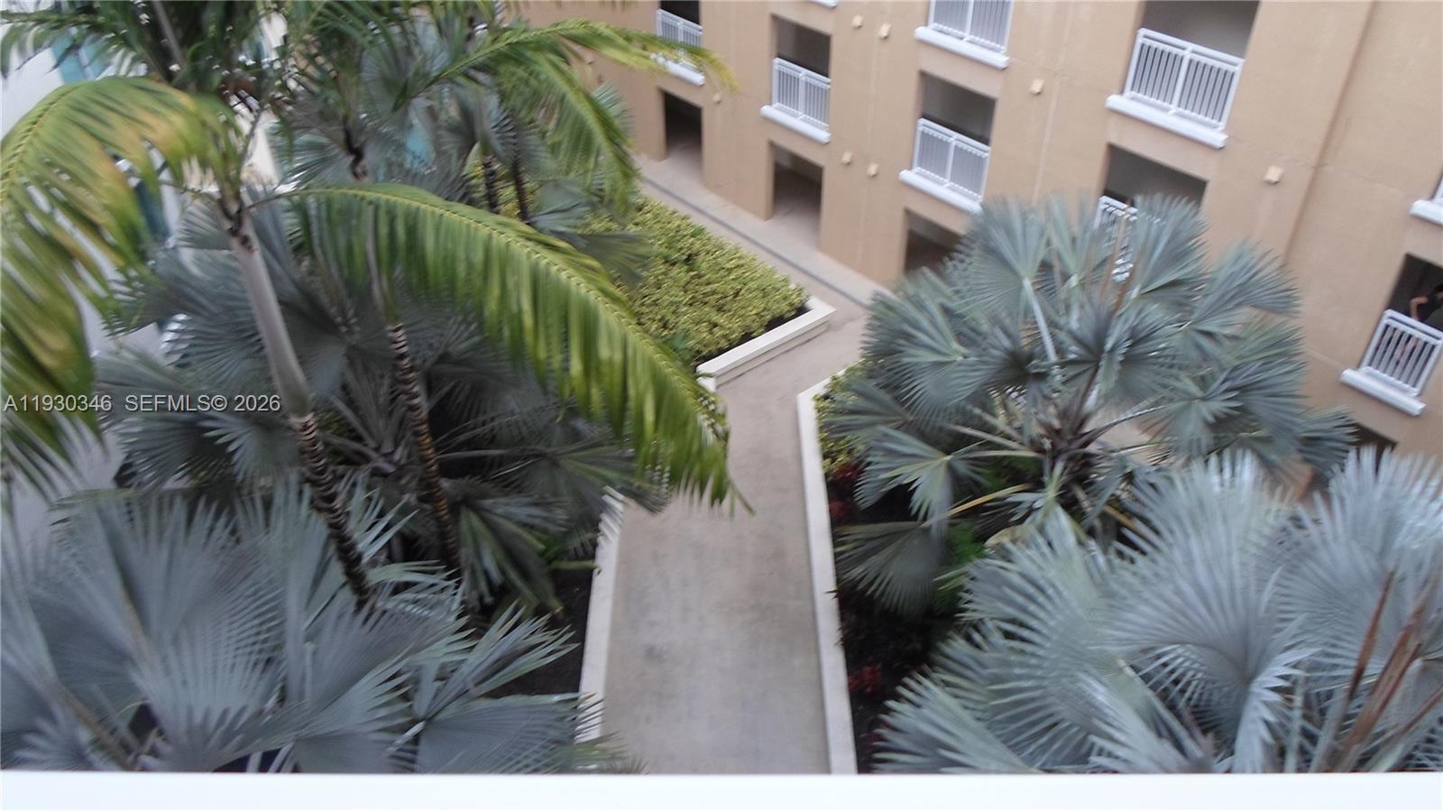 An elevated view shows a concrete walkway winding through a courtyard with palm trees — 7275 SW 90th Way # 611, Miami FL 33156, MIAMI, FL