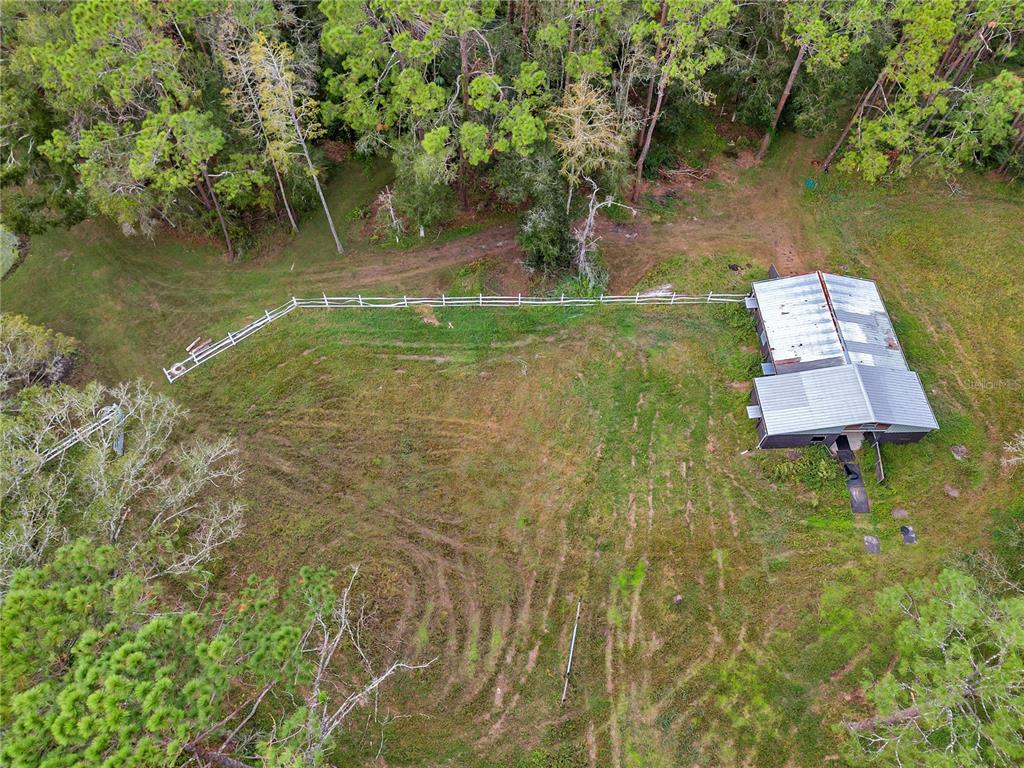 An aerial view shows a metal-roofed barn situated on a grassy lot with white fencing — 0 APPALOOSA ROAD, TARPON SPRINGS, FL