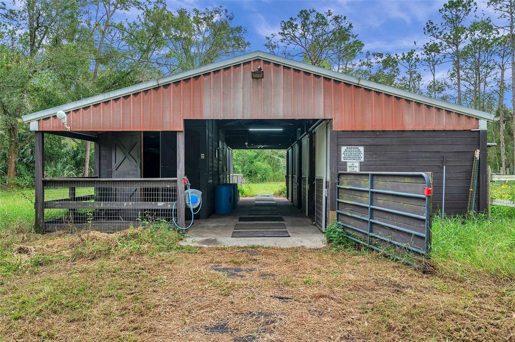A rustic, open-air horse barn with a metal roof and dark wooden stalls — 0 APPALOOSA ROAD, TARPON SPRINGS, FL