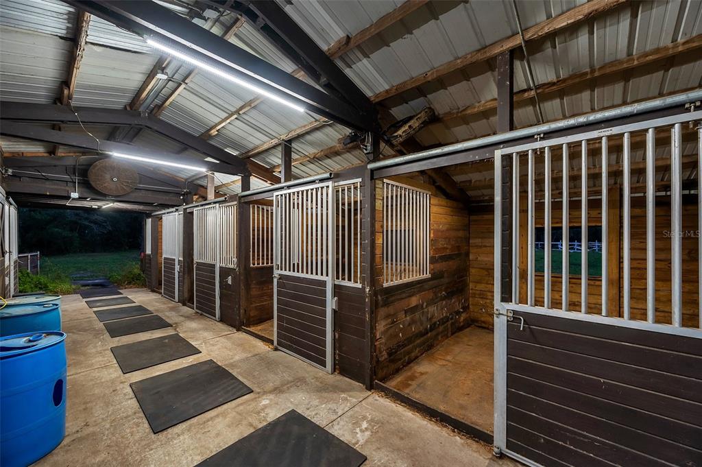 A row of horse stalls with metal gates and wooden walls inside a barn — 0 APPALOOSA ROAD, TARPON SPRINGS, FL