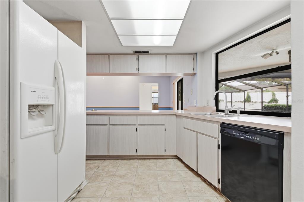 A kitchen features light wood cabinets, white appliances, a black dishwasher, and tile flooring — 9028 PAR COURT, HUDSON, FL