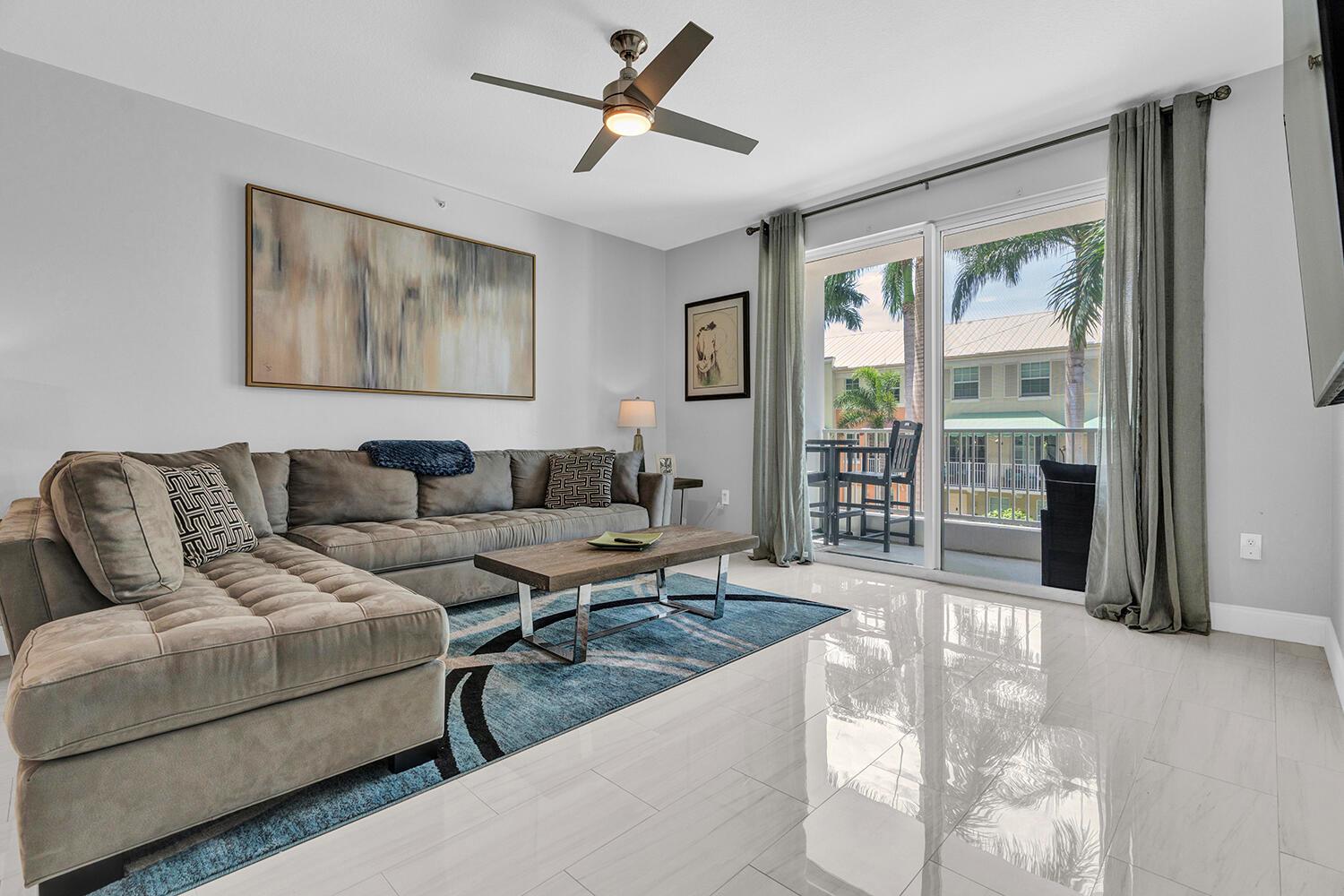 A living room features a grey sectional sofa, a coffee table, and a balcony view — 802 W Windward Way # 217, Lantana FL 33462, LANTANA, FL