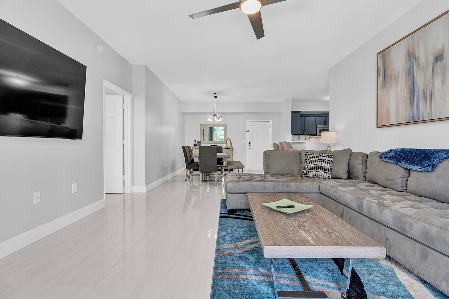 A living room with a grey sectional sofa, blue area rug, and dining area beyond — 802 W Windward Way # 217, Lantana FL 33462, LANTANA, FL