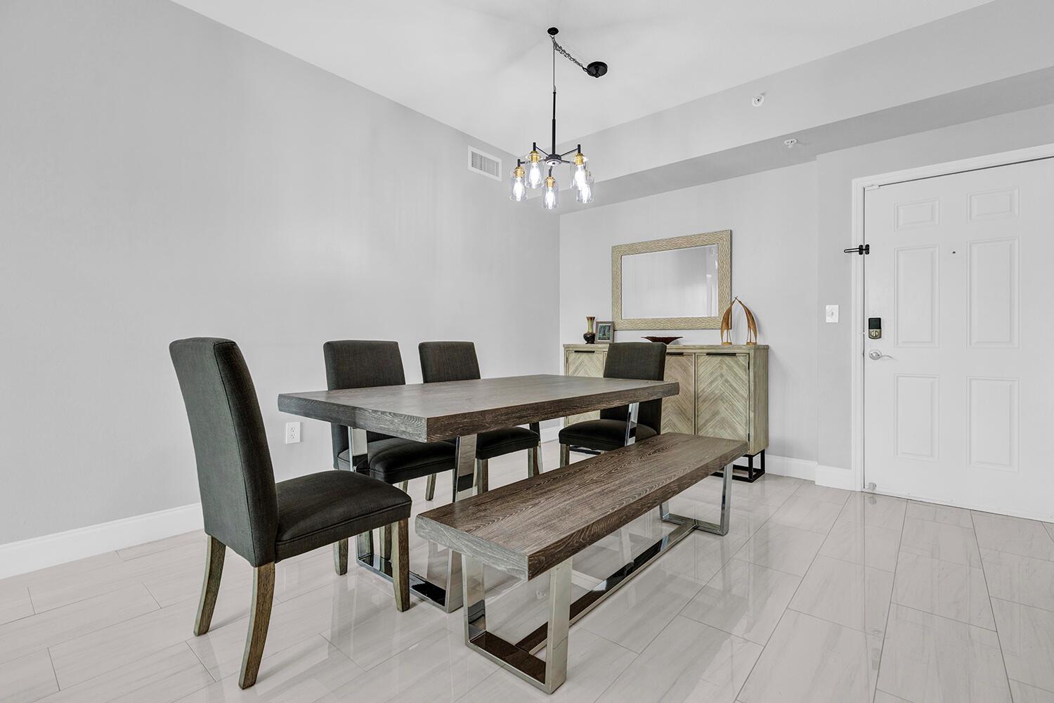 A dining room features a wooden table with a bench, chairs, and a chandelier — 802 W Windward Way # 217, Lantana FL 33462, LANTANA, FL