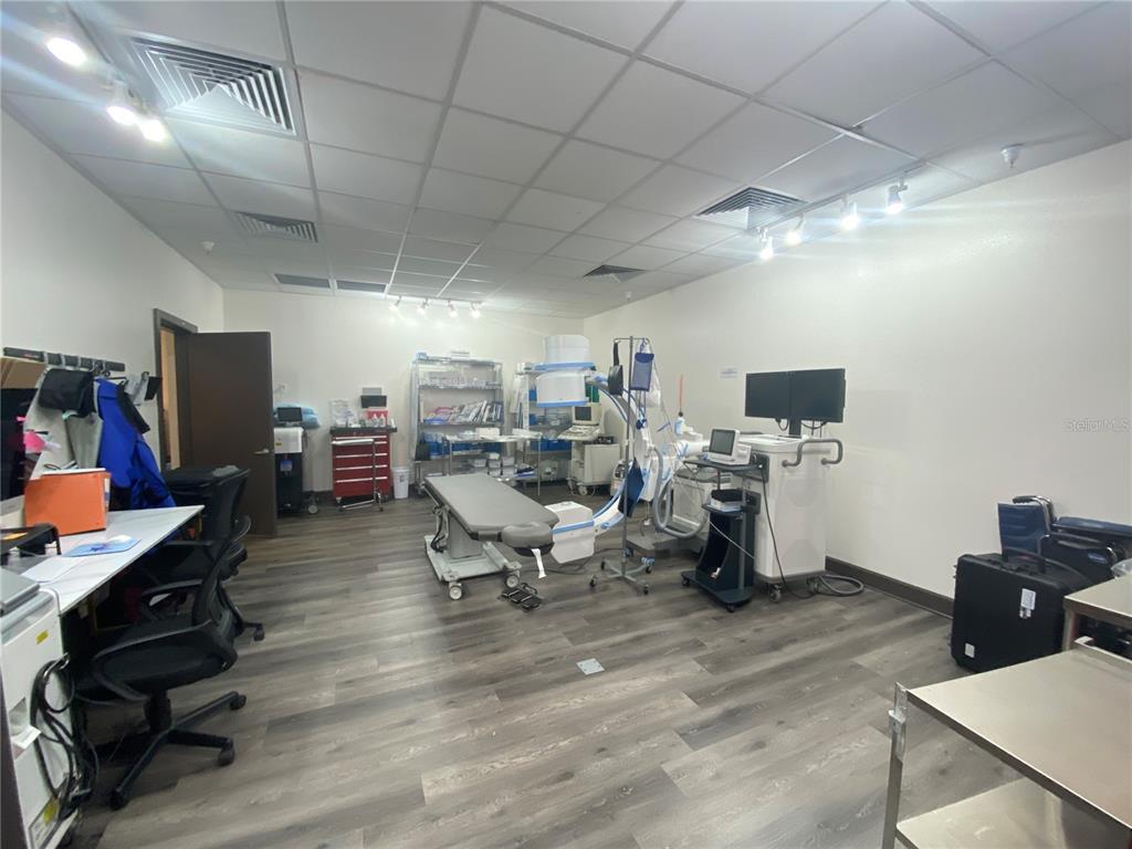 A medical procedure room features a C-arm imaging system, an examination table, and wood-look flooring — 566 OCOEE COMMERCE PARKWAY, OCOEE, FL