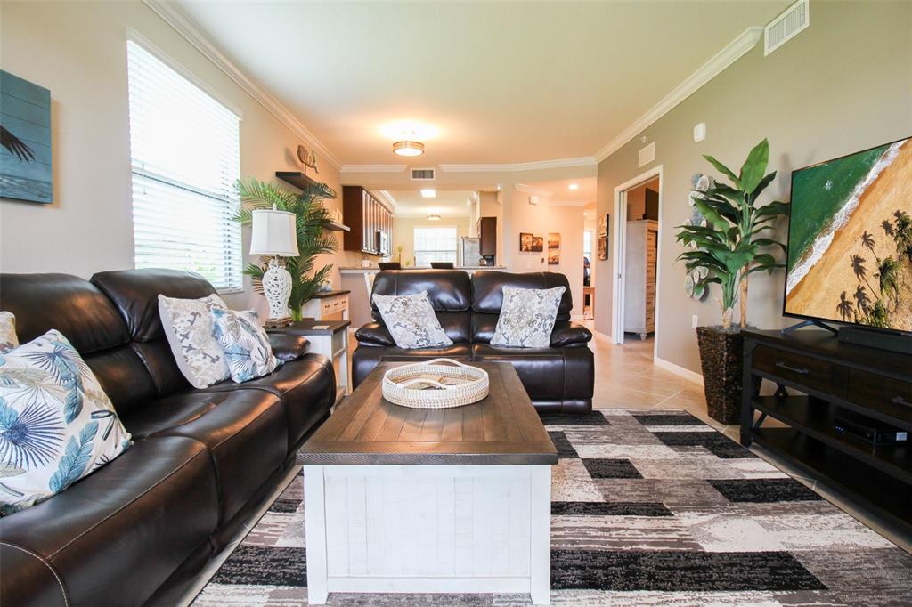 A living room features dark leather sofas, a wooden coffee table, and a television — 16804 VARDON TERRACE UNIT 108, BRADENTON, FL
