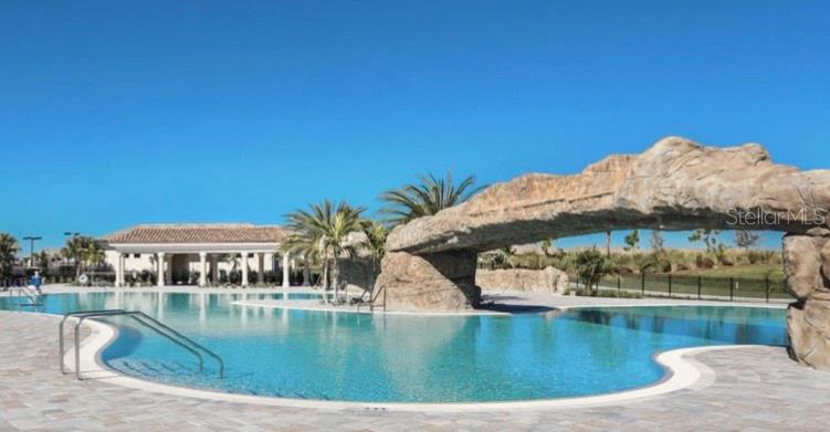 A swimming pool features a large rock formation archway and a nearby covered patio area — 16804 VARDON TERRACE UNIT 108, BRADENTON, FL