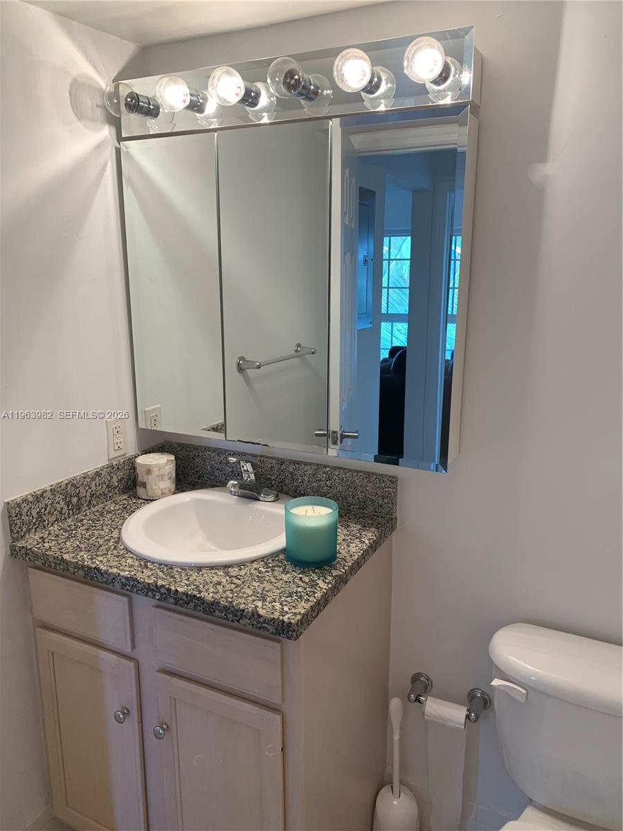 A bathroom features a granite vanity, a mirrored medicine cabinet, and a multi-bulb light fixture — 290 Sunrise Dr # 304, Key Biscayne FL 33149, KEY BISCAYNE, FL