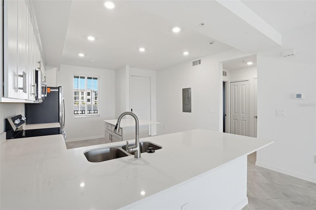 A modern kitchen features white cabinets, quartz countertops, a stainless steel sink, and recessed lighting — 19110 SCALLOP LOOP UNIT 204, LAKEWOOD RANCH, FL