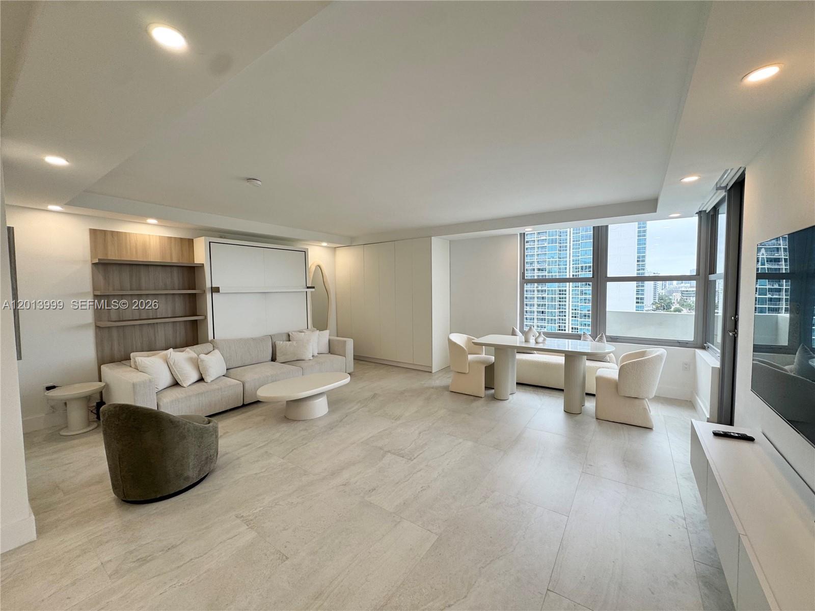 A modern living room features a sofa, dining area, and large windows with city views — 2899 Collins Ave # 1414, Miami Beach FL 33140, MIAMI BEACH, FL