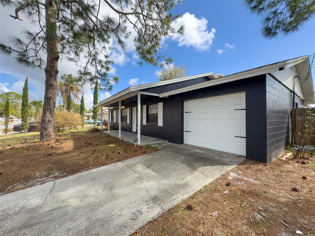 A single-story house with black painted brick walls, a white garage door, and a porch — 4715 GREENHILL STREET, COCOA, FL