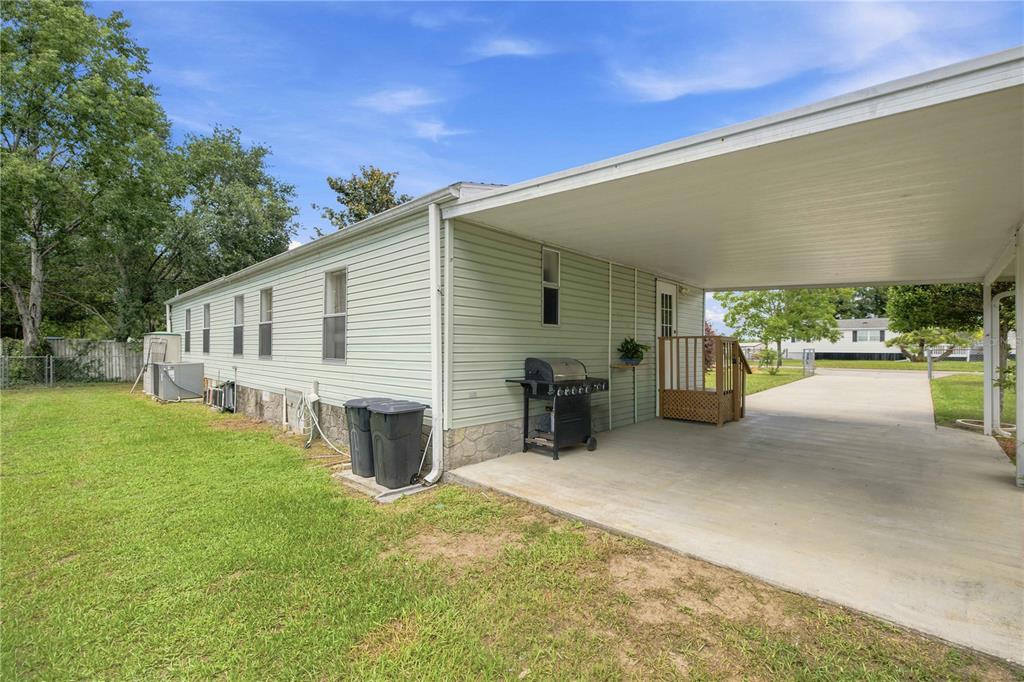 A side view of a light green manufactured home with a concrete carport and lawn — 6720 NE 1ST PLACE, OCALA, FL