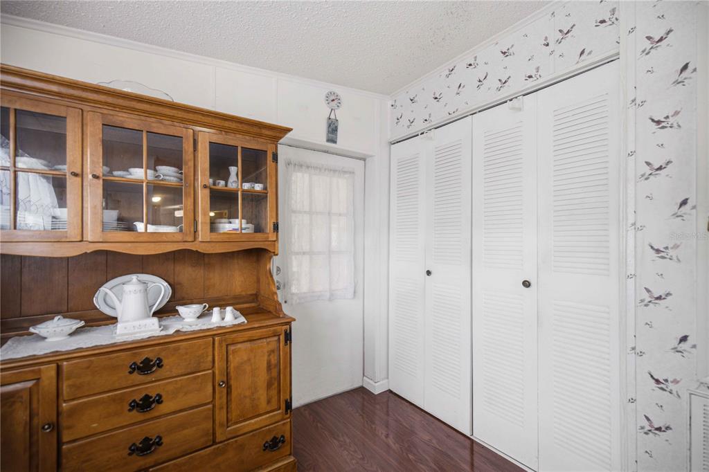 A wooden hutch sits in a room with white louvered closet doors and patterned wallpaper — 6720 NE 1ST PLACE, OCALA, FL