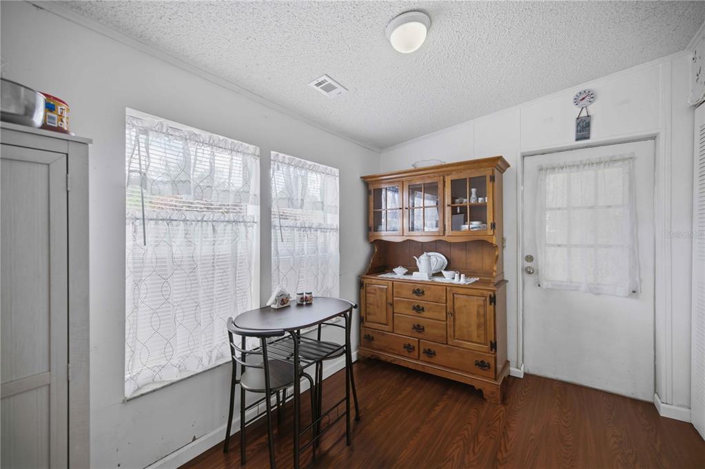 A dining area features wood-look flooring, a small table with two chairs, and a wooden hutch — 6720 NE 1ST PLACE, OCALA, FL