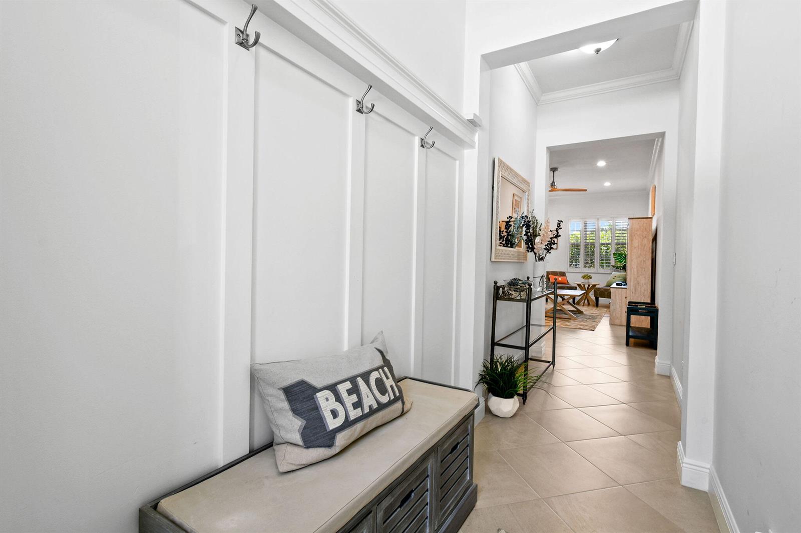 A white hallway features a built-in bench with coat hooks and tile flooring — 106 Ocean Breeze Drive, Juno Beach FL 33408, JUNO BEACH, FL